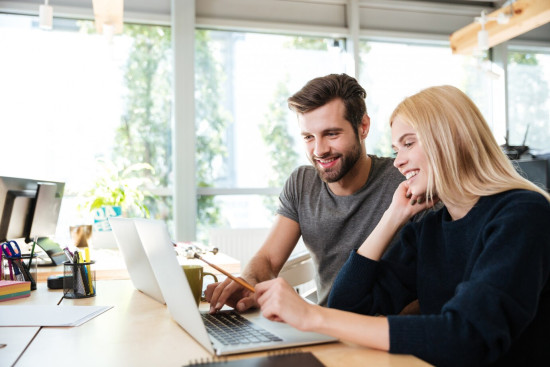 happy colleagues sitting office coworking using laptop